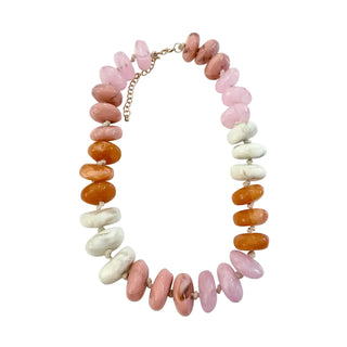 A beaded necklace made of irregular polished stone beads in pink, orange, and white, arranged in a circle on a plain white background.