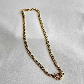 Gold chain necklace on a light gray background