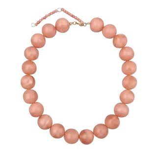 A strand of large, round peach-pink beads with a gold clasp and an extender chain, displayed on a clean white background.