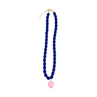A beaded necklace featuring deep blue round beads, a gold-tone clasp and extender chain, and a dangling light pink heart-shaped charm, shown against a plain white background.