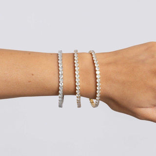 Three pearl bracelets on a wrist against a light gray background