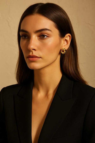 Woman wearing gold earrings against a beige background