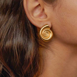Close-up of a person wearing a gold spiral earring.