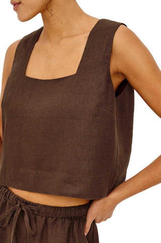 Brown sleeveless top worn by a person on a white background