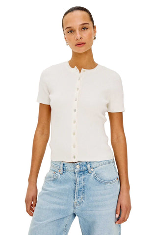 Woman wearing a white short-sleeve shirt and light blue jeans on a plain background