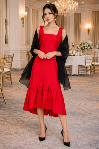 Woman in a red dress with a black cardigan in an elegant indoor setting