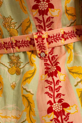 Close-up of a floral patterned shirt with a belt and button details.