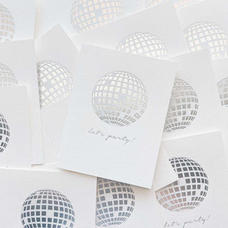 White paper with cut-out disco ball designs and 'let's party!' text on a white background
