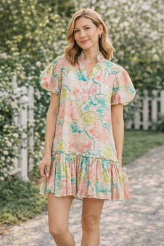 Woman wearing a floral dress standing on a path with greenery in the background