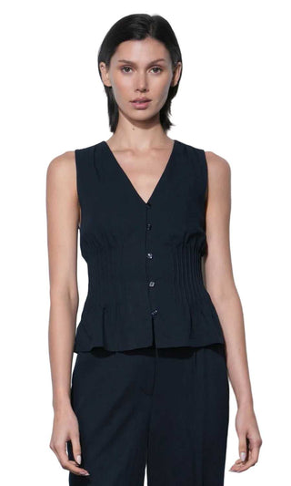 Woman wearing a black sleeveless top and pants against a white background