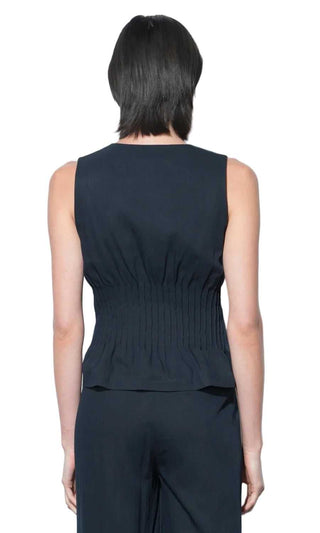 Person wearing a dark sleeveless top and pants against a white background