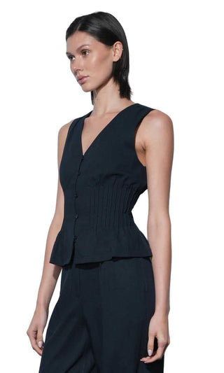 Woman wearing a black sleeveless top and pants against a white background