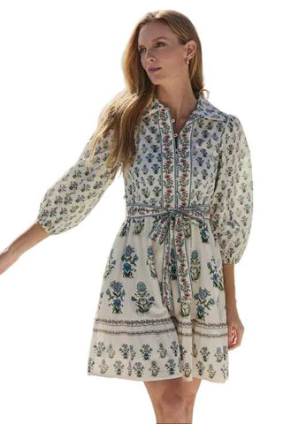 Woman wearing a floral dress standing outdoors with a scenic background