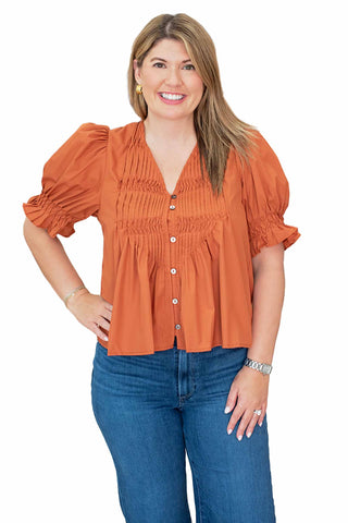 
Entro Kyla top featuring smocked bodice detail, gathered puff sleeves, V-neckline and button-front closure available in chestnut and burgundy colors