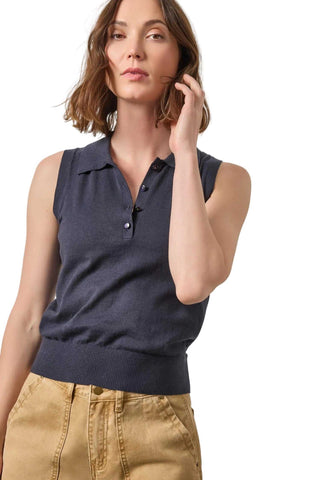 Woman wearing a navy sleeveless polo shirt against a light background