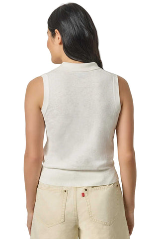 Woman wearing a white sleeveless top and beige pants on a light gray background