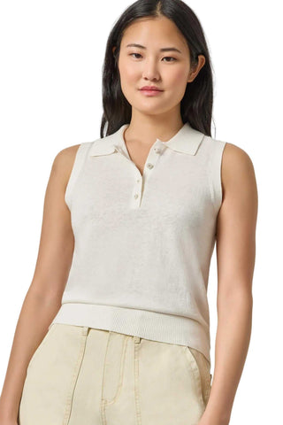 Woman wearing a sleeveless beige knit top against a plain background