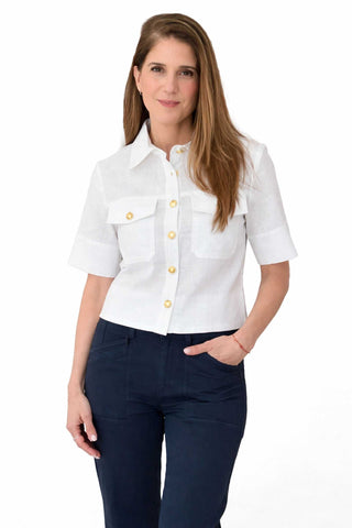 Woman wearing a white blouse with Gold buttons and dark pants on a white background