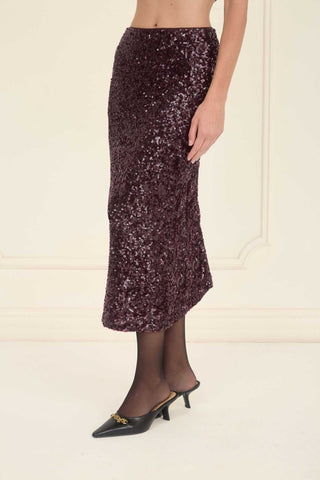 Person wearing a dark sequin skirt on a plain background