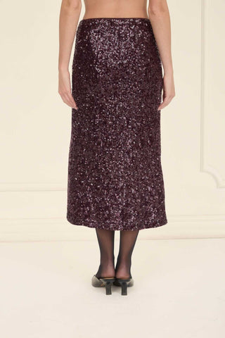 Person wearing a sequin skirt on a plain background