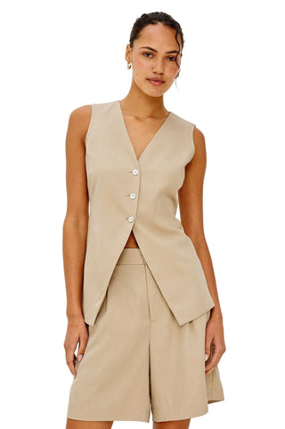Woman wearing a beige vest and shorts set on a plain background
