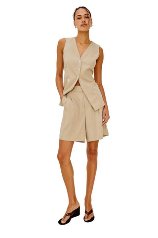 Woman wearing a beige vest and skirt set on a white background