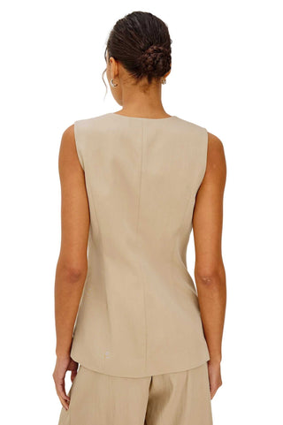 Woman wearing a beige sleeveless top and pants on a white background