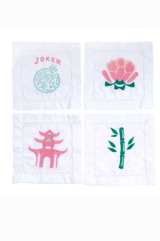 Set of four white embroidered cocktail napkins with pink and green mahjong tile designs including joker, flower, pagoda, and bamboo motifs
