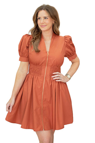 Entro Mia dress in pumpkin orange featuring puff sleeves, smocked waist, gold zip front closure and fit-and-flare silhouette for fall fashion