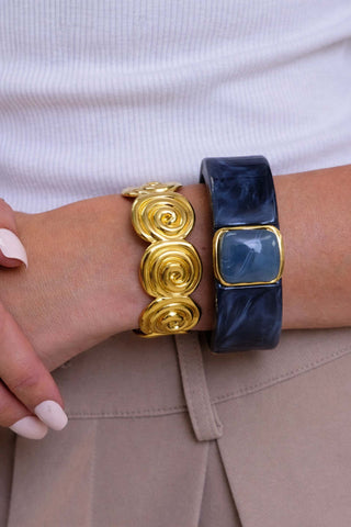 Gold and blue bracelets on a wrist against a white background