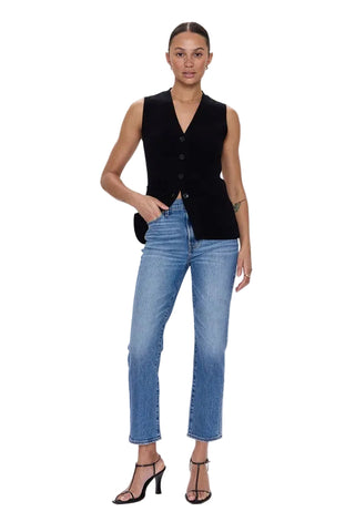 Woman wearing a black vest and blue jeans on a white background