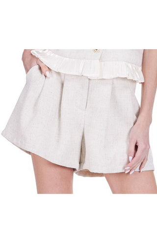 Tailored shorts with front pleats, side pockets, and elastic back waist detail on white background