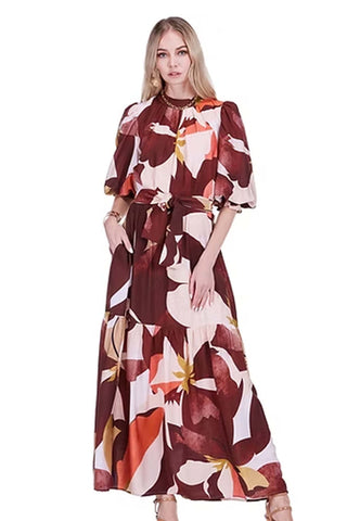 Jade Pleated Neck Maxi in Harvest Rhythm. Burgundy and coral floral print maxi dress with pleated high neck, puffed three-quarter sleeves, and tie waist 