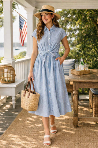 Woman in a blue striped dress standing on a porch with an American flag in the background