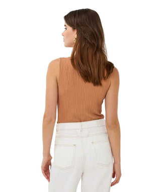 Woman wearing a brown ribbed tank top and white pants on a white background
