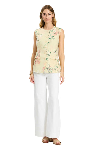 Woman wearing a floral sleeveless top and white pants on a white background