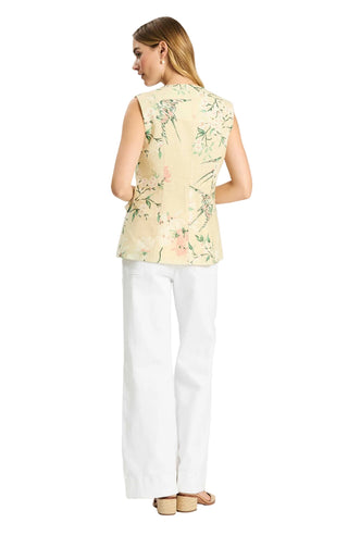 Woman wearing a light-colored sleeveless top with floral pattern and white pants on a white background