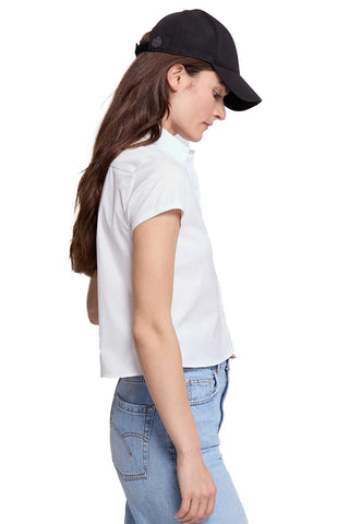 Woman wearing a white shirt, black cap, and light blue jeans on a white background