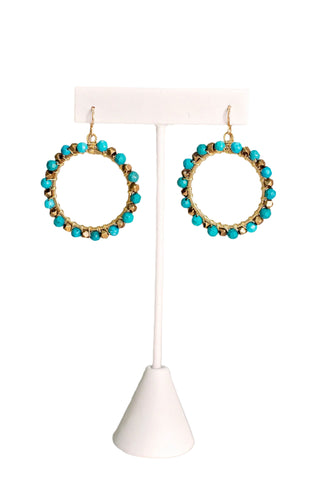 Handcrafted gold hoop earrings with turquoise and bronze beads displayed on white jewelry stand against neutral background - one-of-a-kind bohemian statement jewelry