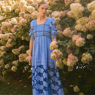 Woman in a blue dress standing among flowers