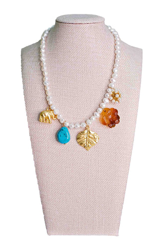 Knotty Bling Zuma multi charm pearl necklace featuring gold elephant, turquoise teardrop, amber flower charms and gold leaf accents on freshwater pearl strand