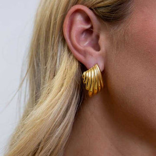 Gold hoop earring worn by a person with blonde hair.