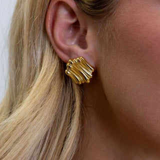 Gold textured earring worn by a person with blonde hair.