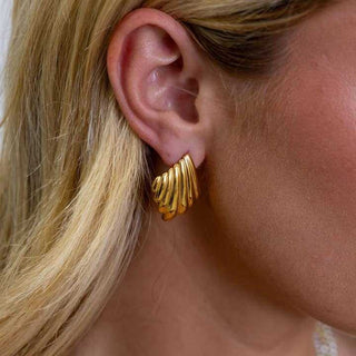 Gold hoop earrings worn by a person with blonde hair.
