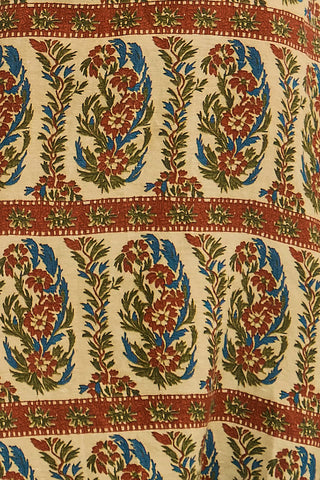 A close-up of a printed textile pattern featuring vertical floral motifs in red, blue, and green on a warm cream background, with horizontal rust-red decorative bands.