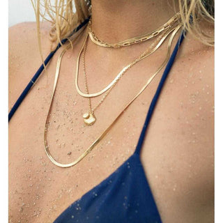 Close-up of a person wearing gold necklaces with a blue top.