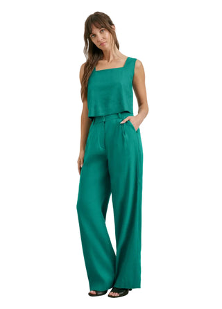 Woman wearing a green jumpsuit against a plain background