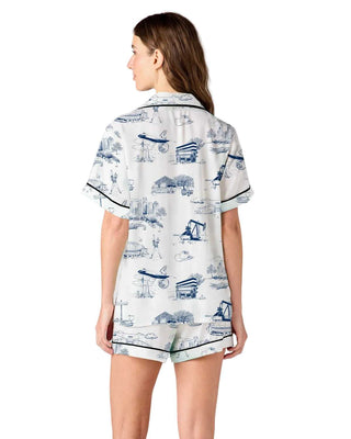 Woman wearing a pajama set with a blue and white pattern on a plain background