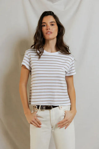 Woman wearing a striped shirt and white pants against a plain background