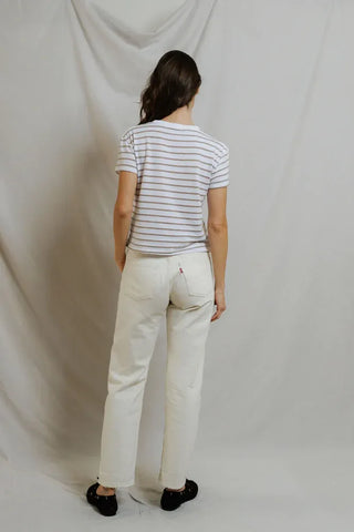 Person wearing a striped shirt and white pants against a plain background